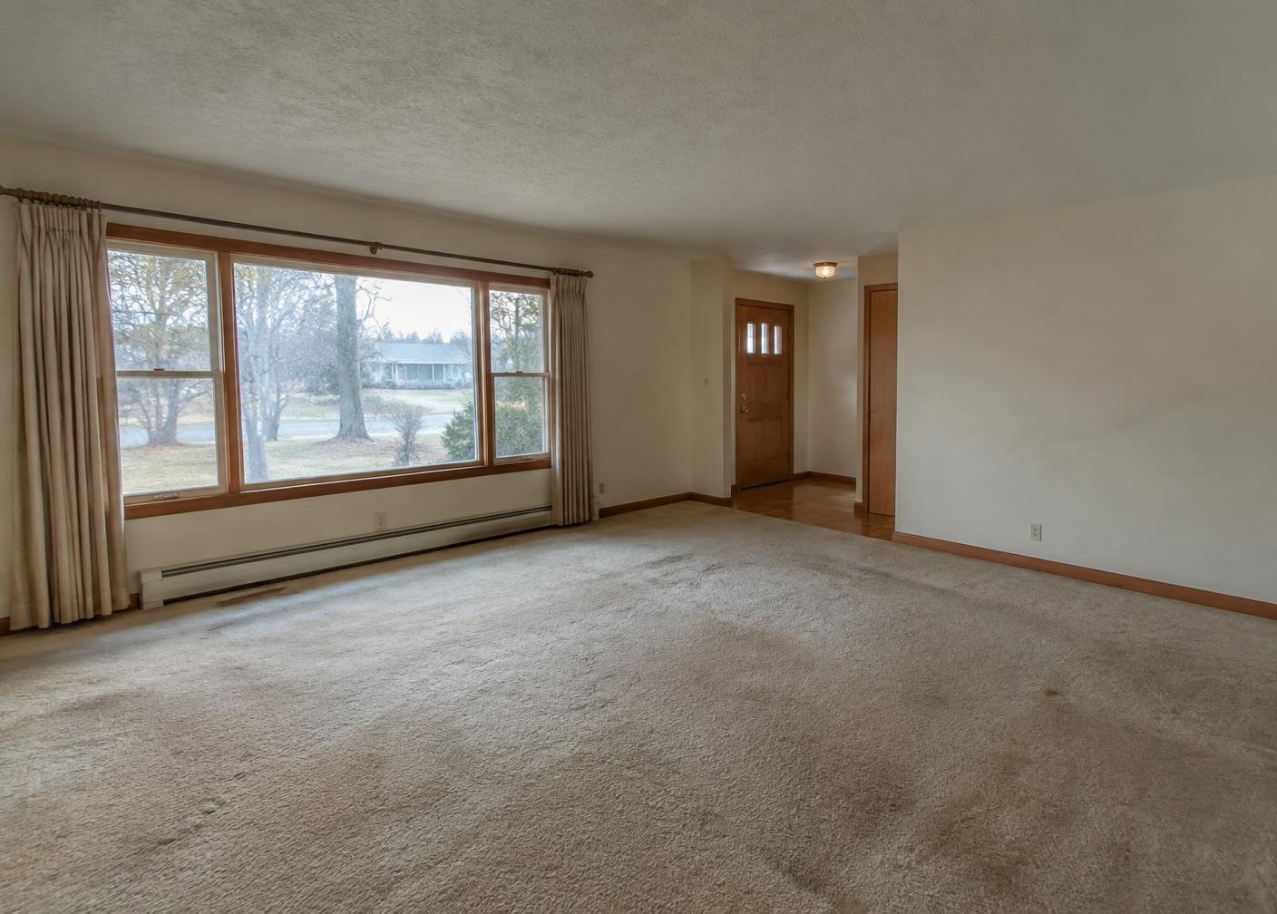 Living room before flooring installation, with worn carpet