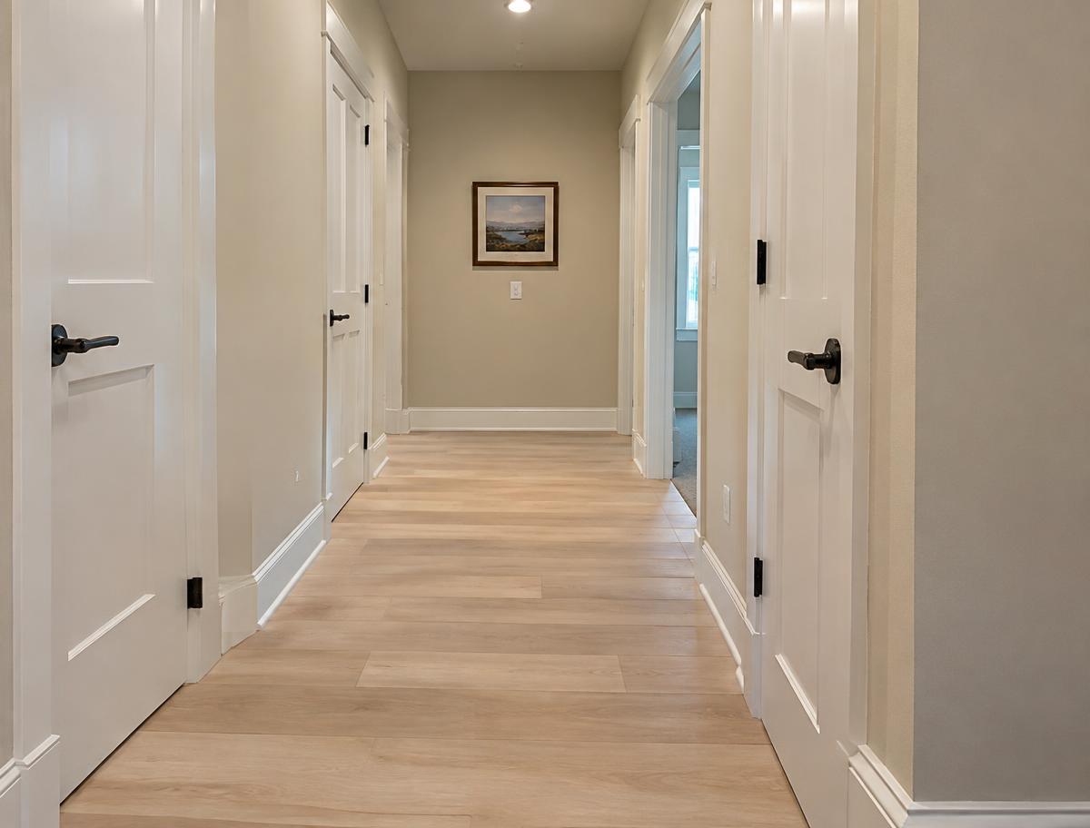 Hallway with light laminate flooring and new white baseboards